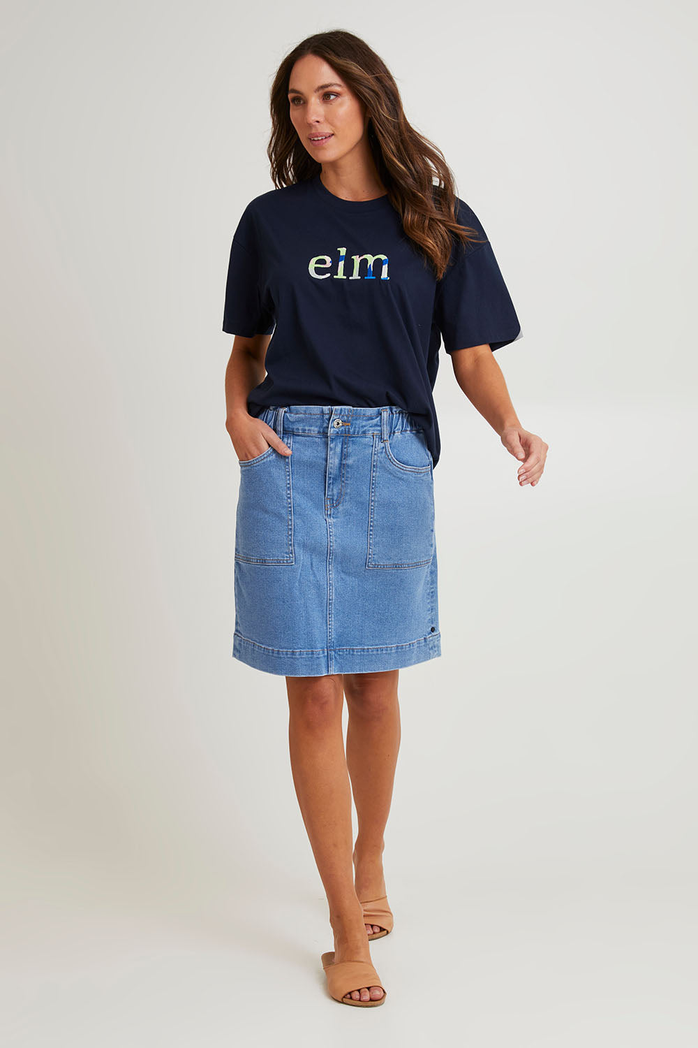 Model Madeline wearing size 10 of the Atlas Denim Skirt in colour Midblue (Blue), from the front, showing the whole outfit