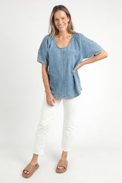 A model wearing the Brea Top in colour Bluewash (Blue), from the front, showing the whole outfit