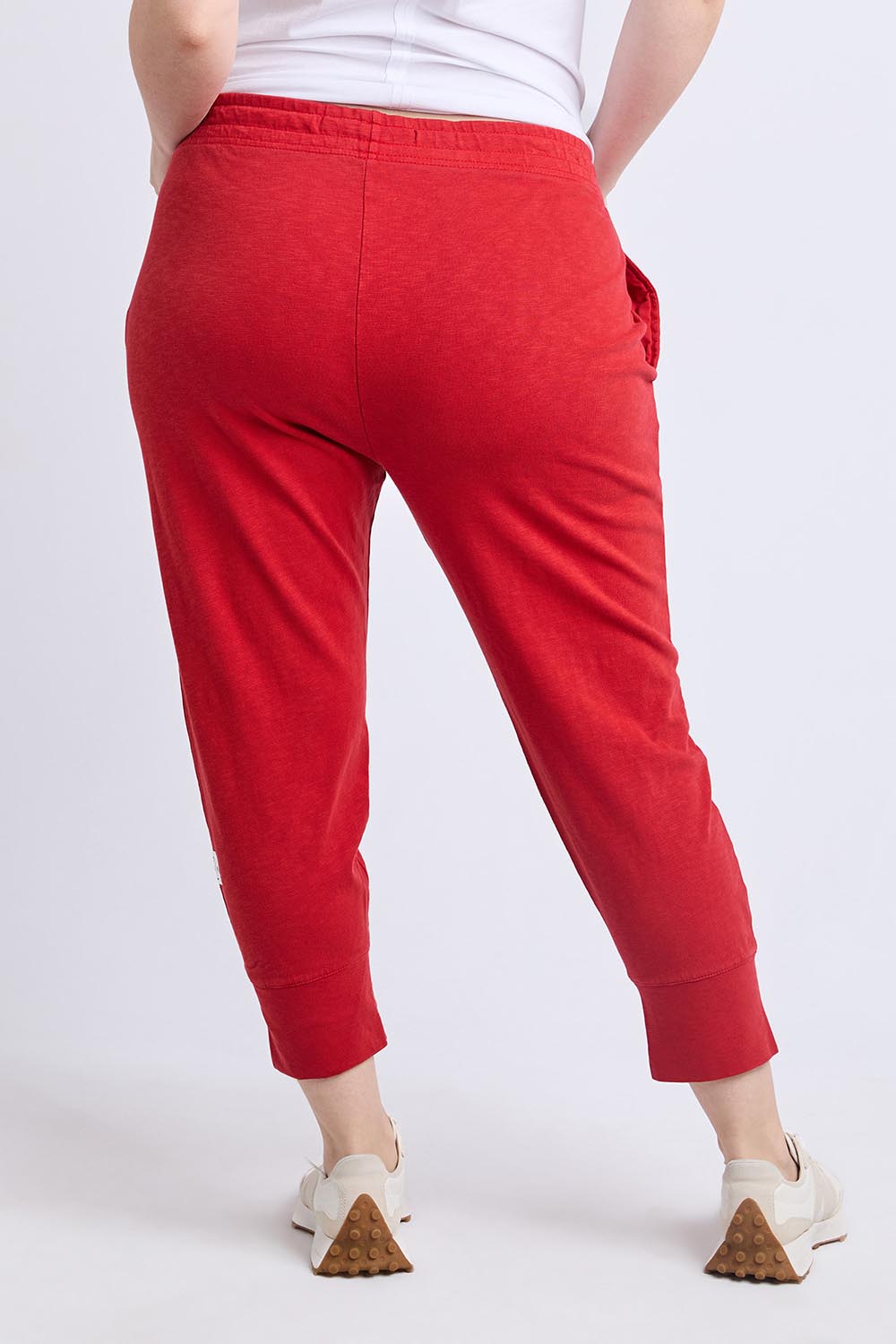 A model wearing the Fundamental Brunch Cotton Pant in colour Cranberry (Red), from the back
