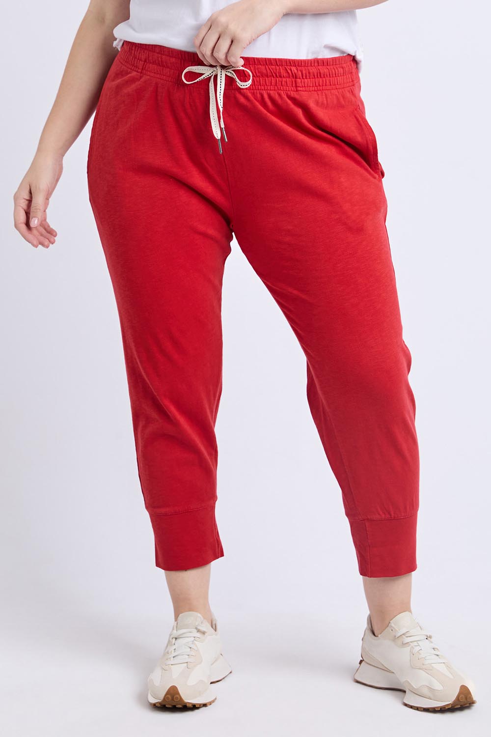 A model wearing the Fundamental Brunch Cotton Pant in colour Cranberry (Red), from the front, cropped image