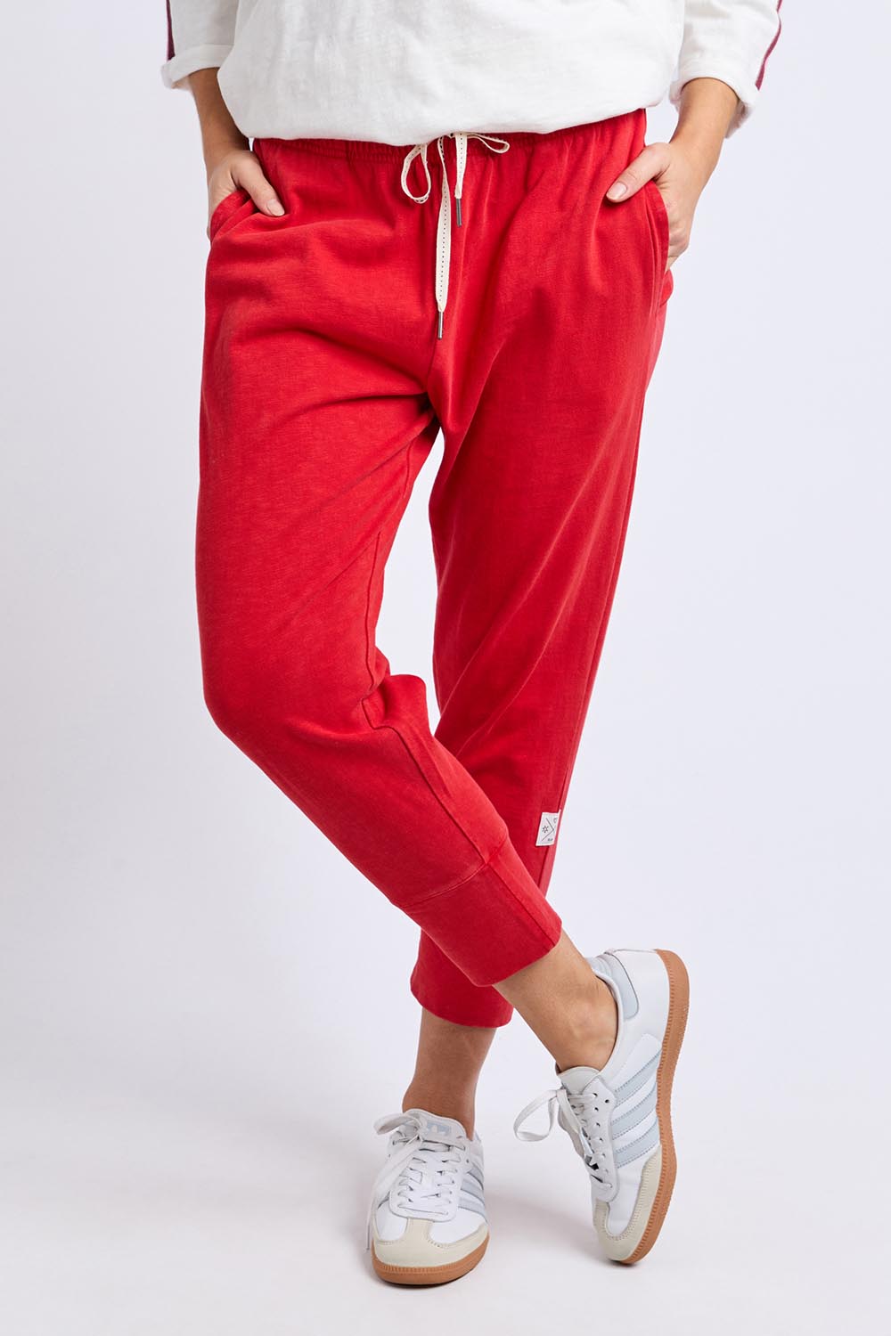 A model wearing the Fundamental Brunch Cotton Pant in colour Cranberry (Red), from the front, cropped image