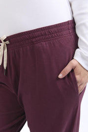 A model wearing the Fundamental Brunch Cotton Pant in colour Merlot (Red), from the front, cropped image
