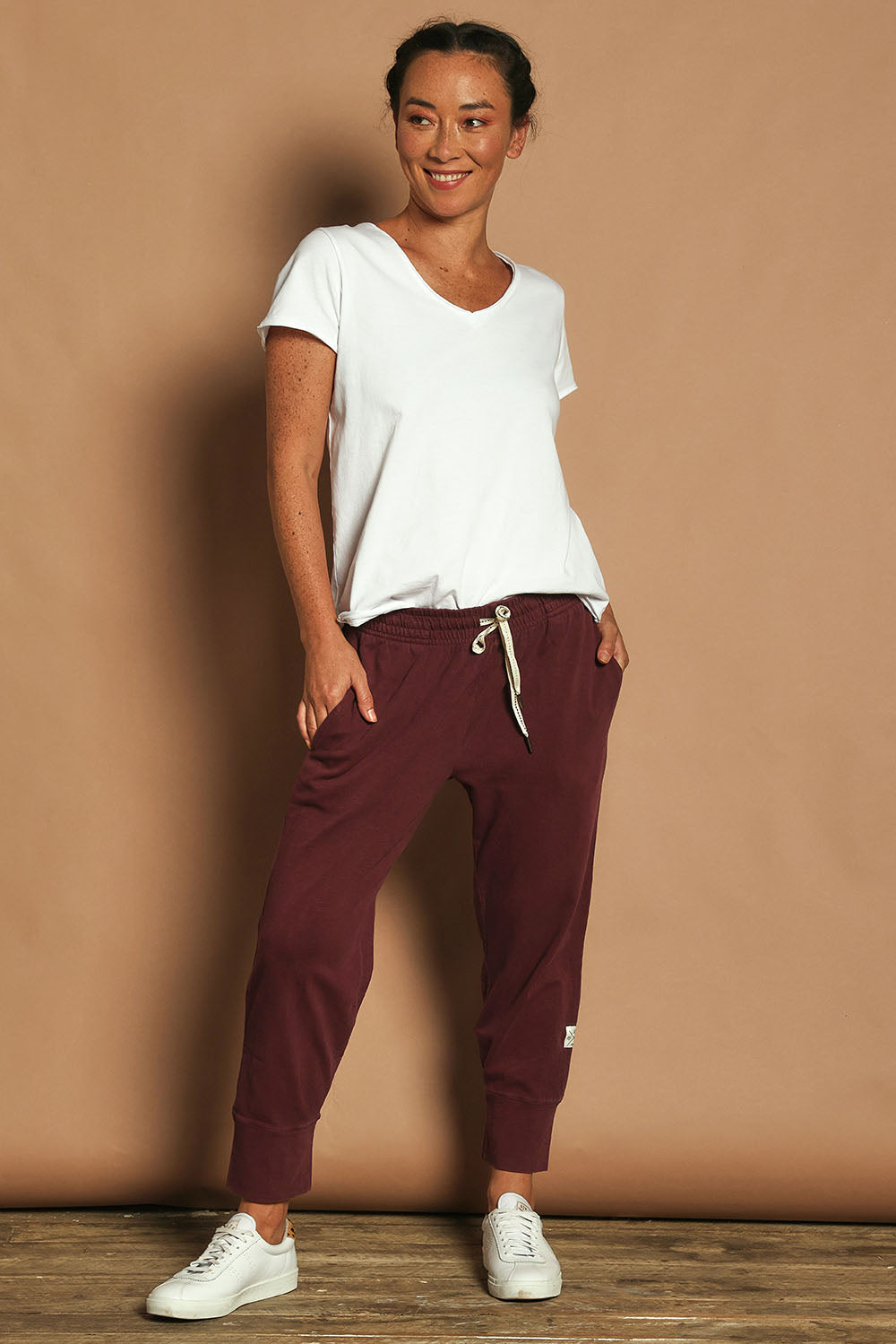 Model Katie wearing size 10 of the Fundamental Brunch Cotton Pant in colour Merlot (Red), from the front, showing the whole outfit