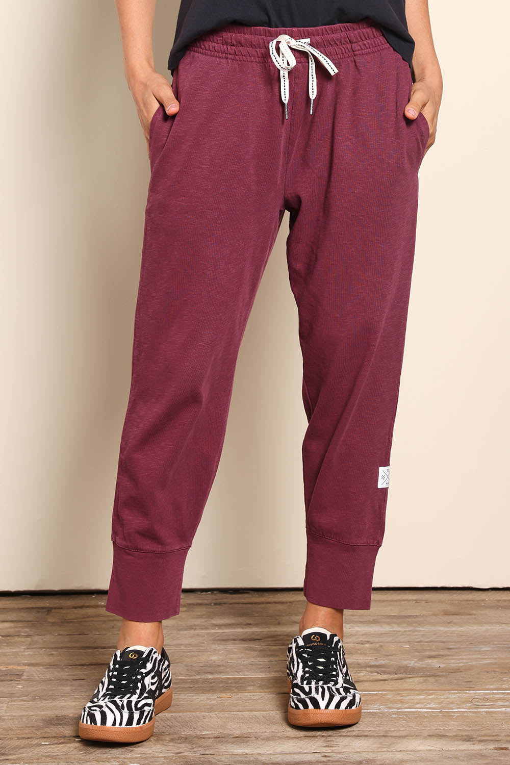 Model Pamelar wearing size 10 of the Fundamental Brunch Cotton Pant - Merlot in colour Merlot, in a cropped view