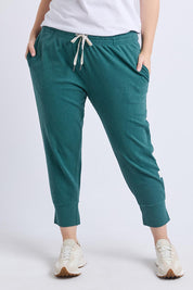 A model wearing the Fundamental Brunch Cotton Pant in colour Teal (Green), from the front, cropped image