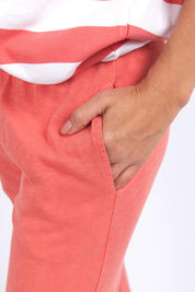 A model wearing the Fundamental Brunch Cotton Pant in colour Watermelon (Red), from the front, cropped image