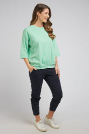 A model wearing the Fundamental Mazie Cotton Sweat Top in colour Mistymoss (Green), from the front, showing the whole outfit