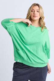 A model wearing the Fundamental Mazie Cotton Sweat Top in colour Springgree (Green), from the front, cropped image