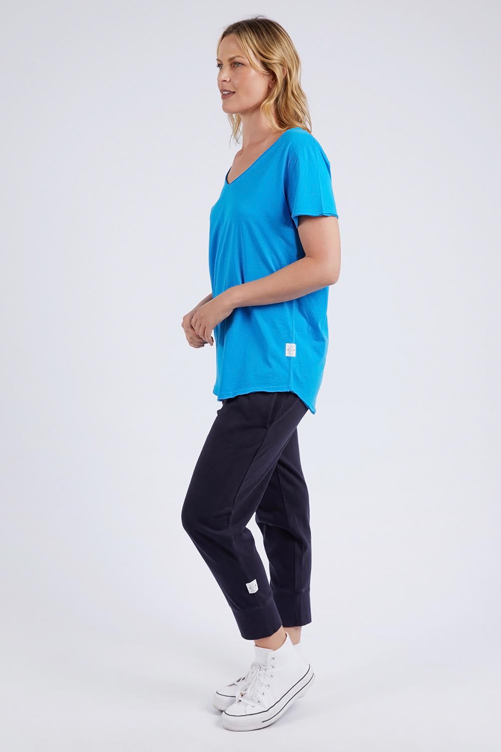 A model wearing the Fundamental Vee Cotton Tee in colour Ibizablue (Blue), from the front, showing the whole outfit