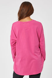 Model Cara wearing size 10 of the Fundamental Society L/S Tee in colour Raspberry (Pink), from the back