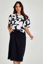 Model Madeline wearing size 10 of the Fundamental Rib Midi Skirt in colour Navy (Blue), from the front, cropped image