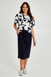 Model Madeline wearing size 10 of the Fundamental Rib Midi Skirt in colour Navy (Blue), from the front, showing the whole outfit