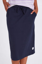 Model Olivia wearing size 10 of the Fundamental Rib Midi Skirt in colour Navy (Blue), from the front, cropped image