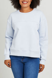 Model Olivia wearing size 10 of the Fundamental Shelly Fleece Crew in colour Lightblue (Blue), from the front, cropped image