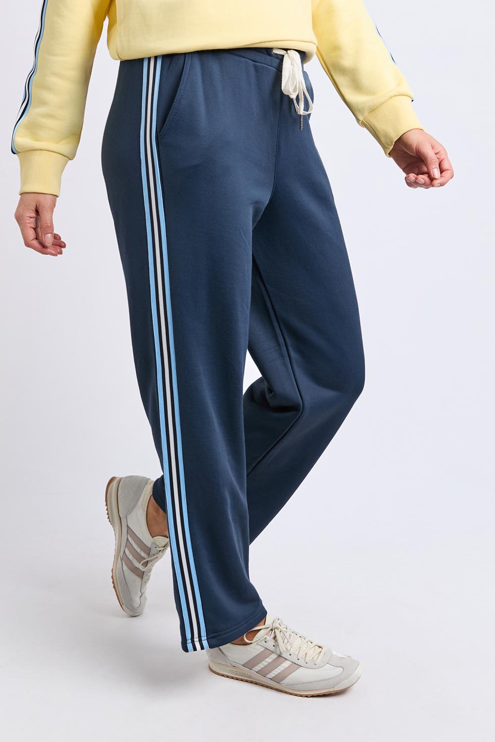 A model wearing the Fundamental Amara Trackpant in colour Navystripe (Blue), from the front, cropped image