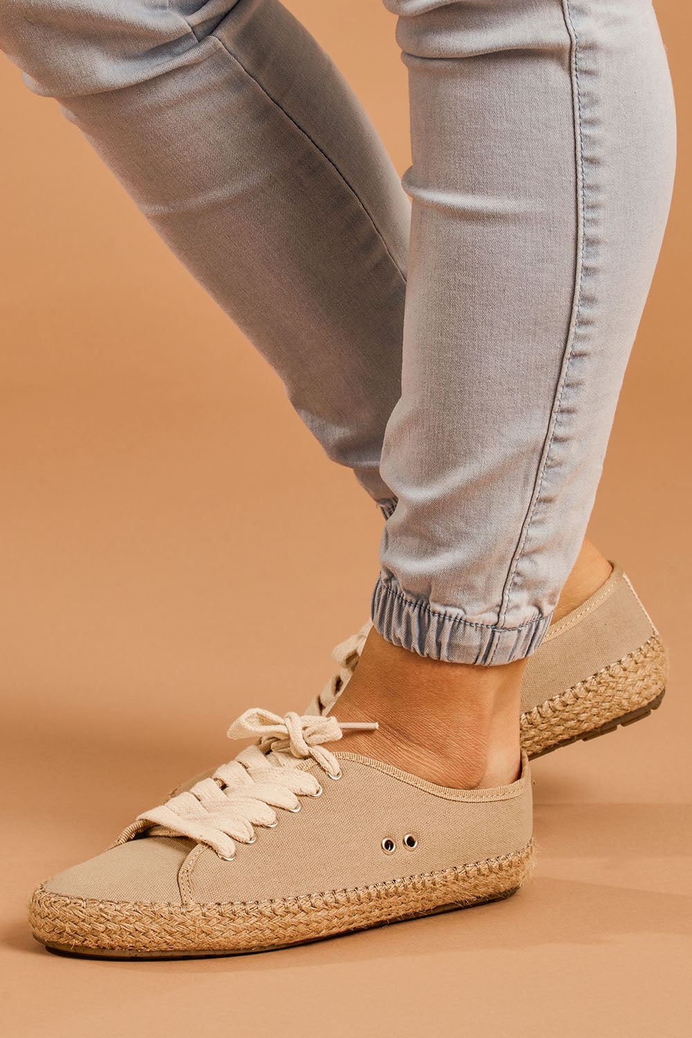 A model wearing size 8 of the Agonis Organic Sneaker in colour Almond, from the front, cropped image
