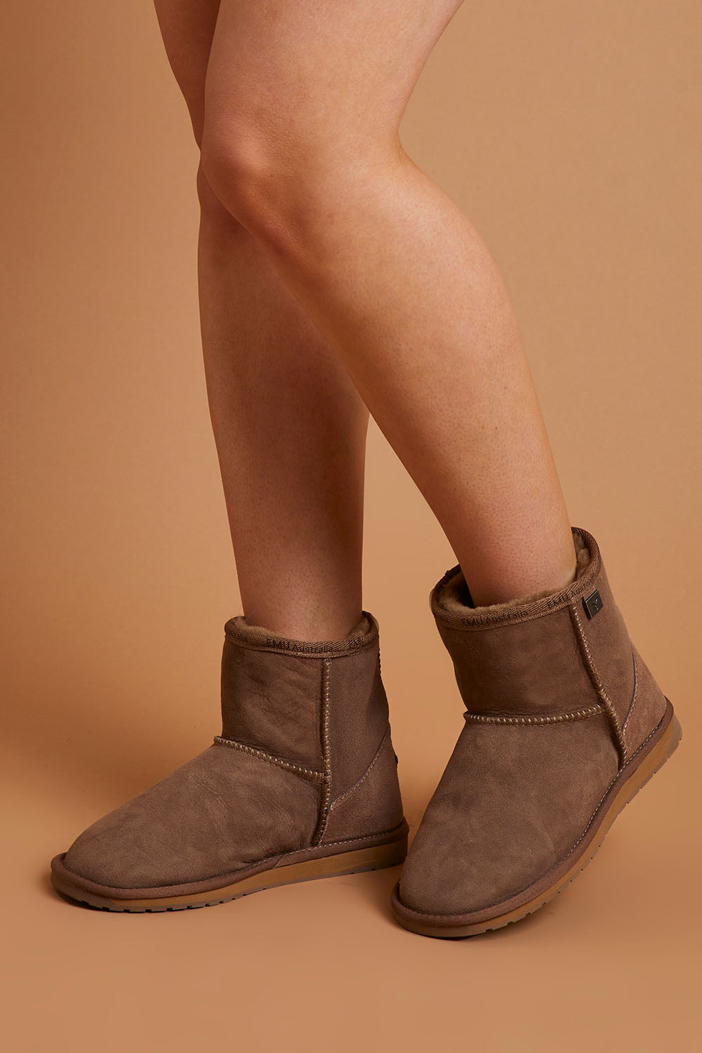 A model wearing size 8 of the Platinum Stinger Mini Ugg Boots in colour Mushroom, from the front, showing the whole outfit
