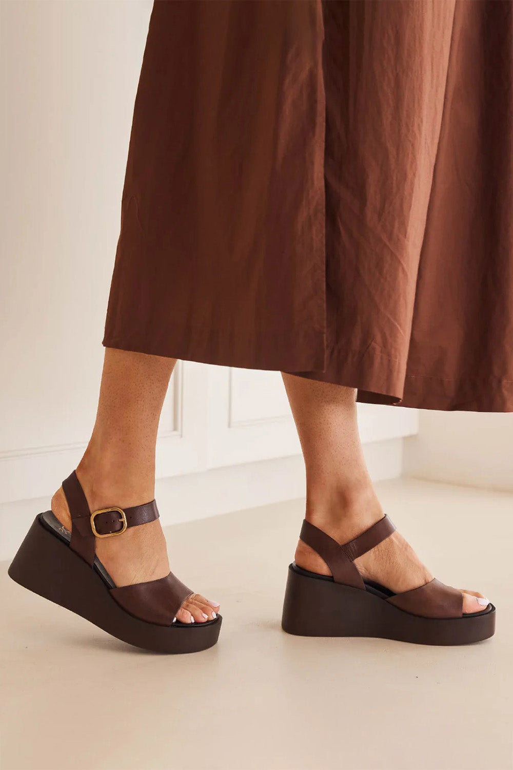 A model wearing the Ariya Leather Wedge in colour Chestnut, from the front, showing the whole outfit