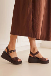 A model wearing the Ariya Leather Wedge in colour Chestnut, from the front, showing the whole outfit
