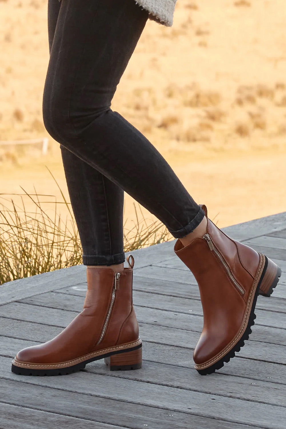 A model wearing the Lindira Double Zip Leather Ankle Boot in colour Brandy, from the front, showing the whole outfit