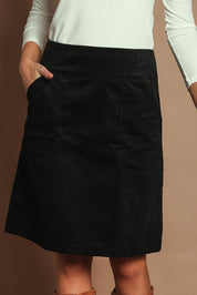 Model Madeline wearing size S of the Amy Cord Skirt in colour Black (Black), from the front, cropped image