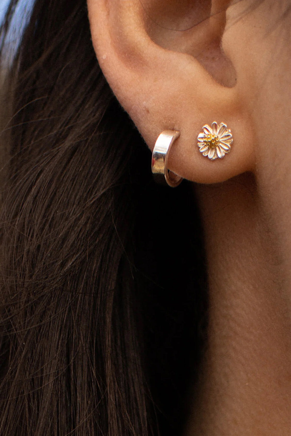 A model wearing the Mini Wildflower Stud Earrings in colour Silver (Metallics), from the front, cropped image