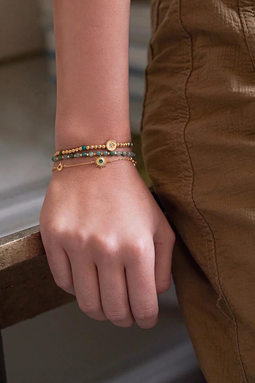 A model wearing the Enamel North Star Bead Bracelet in colour Goldgreen (Metallics), from the front, cropped image