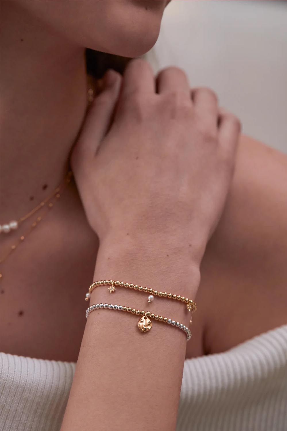 A model wearing the Hammered Charm Beaded Bracelet in colour Silvergold (Metallics), from the front, cropped image