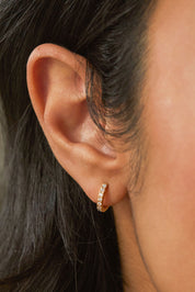 A model wearing the Pave Set Hoop Earrings in colour Gold (Metallics), from the front, cropped image