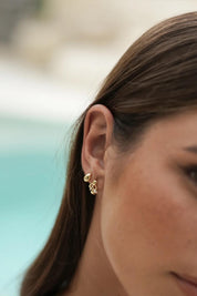 Model Genericm wearing size sample of the Mini Teardrop Earrings – Gold in colour Gold, from an angle