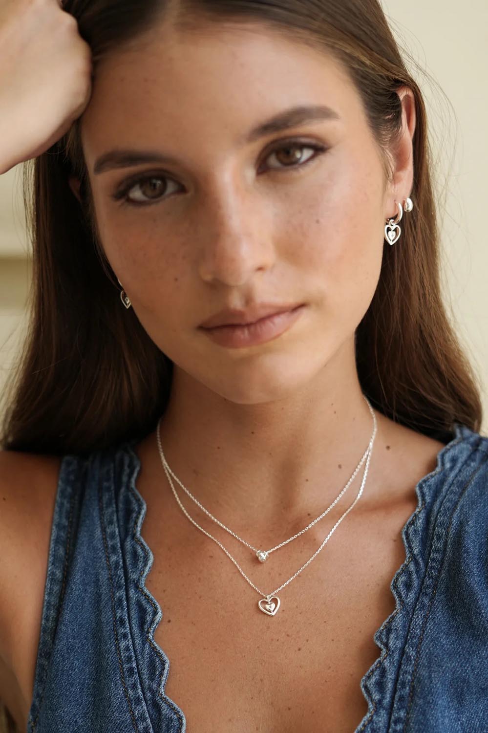 Model Genericm wearing size sample of the Mini Teardrop Earrings – Silver in colour Silver, in a cropped view