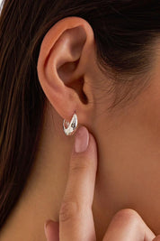 Model Genericm wearing size sample of the Hammered Huggie Hoops – Silver in colour Silver, from an angle