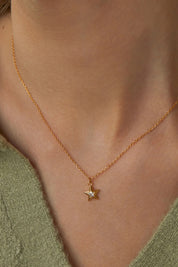 A model wearing the Blue Star Necklace in colour Gold (Metallics), from the front, cropped image
