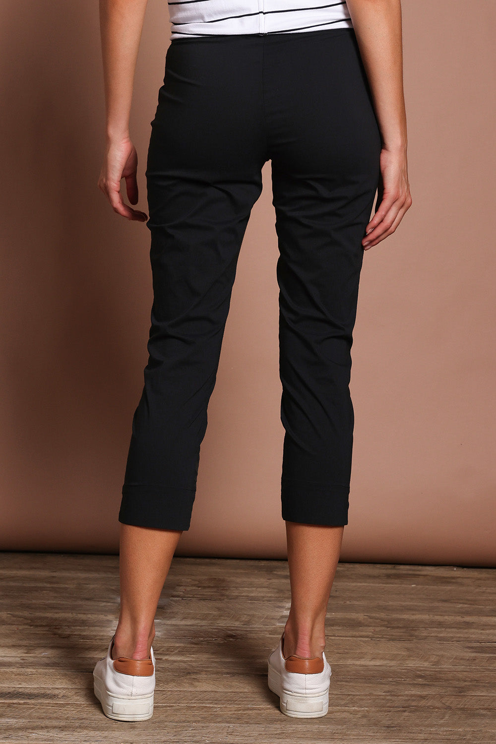 Model Madeline wearing size 10 of the Fuss Free 7/8 Pant in colour Black (Black), from the back
