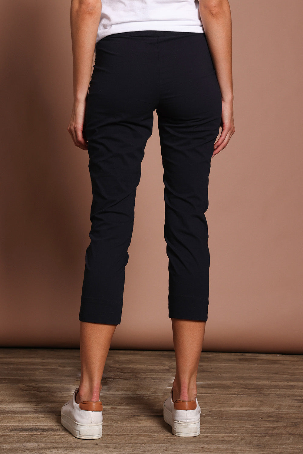 Model Madeline wearing size 10 of the Fuss Free 7/8 Pant in colour TrueNavy (Blue), from the back