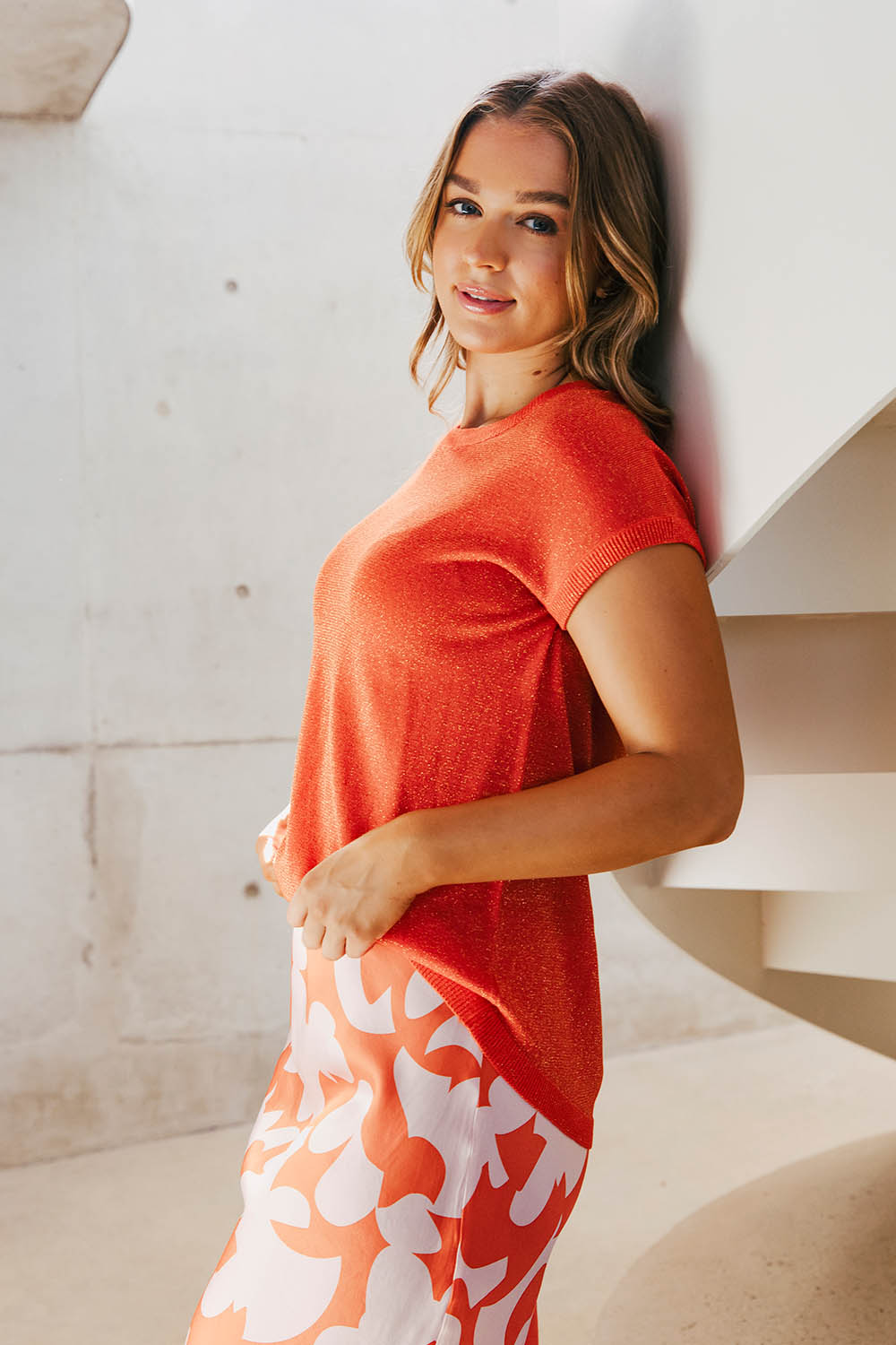A model wearing the Alma Metallic Knit in colour Spcyorange, from the front, showing the whole outfit