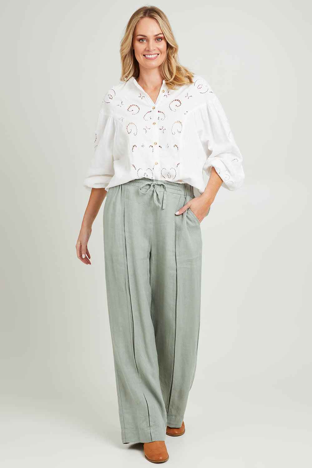 Model Grace wearing size 10 of the Naples Pant in colour Sage Green (Green), from the front, showing the whole outfit