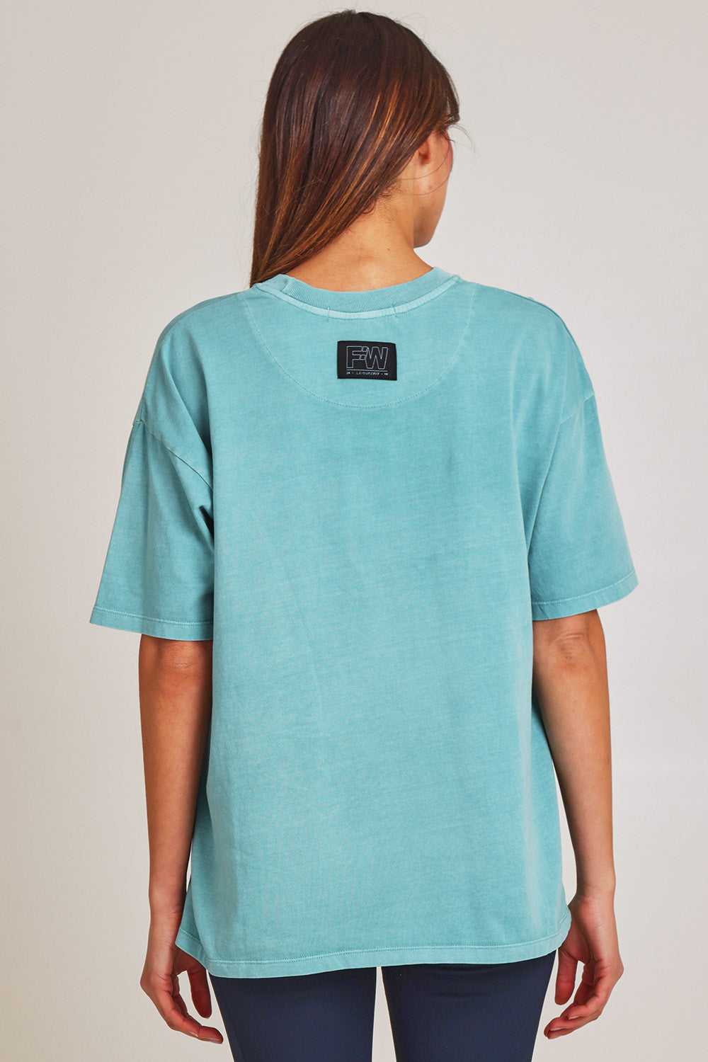 Model Madeline wearing size 10 of the Leisure Captain Cotton Tee in colour Sky (Blue), from the back