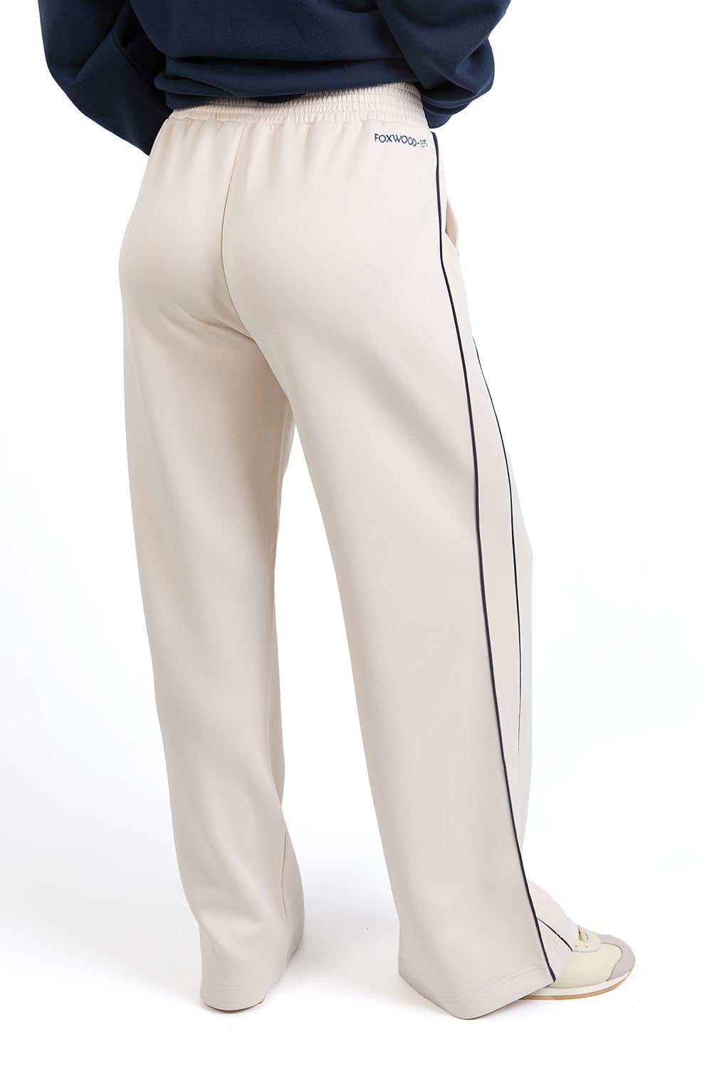 A model wearing the Traveller Pant in colour Bone, from the back