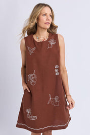 A model wearing the Paradise Cotton Linen Dress in colour Chocolate, from the front, cropped image