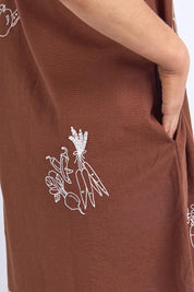 A model wearing the Paradise Cotton Linen Dress in colour Chocolate, from the front, cropped image