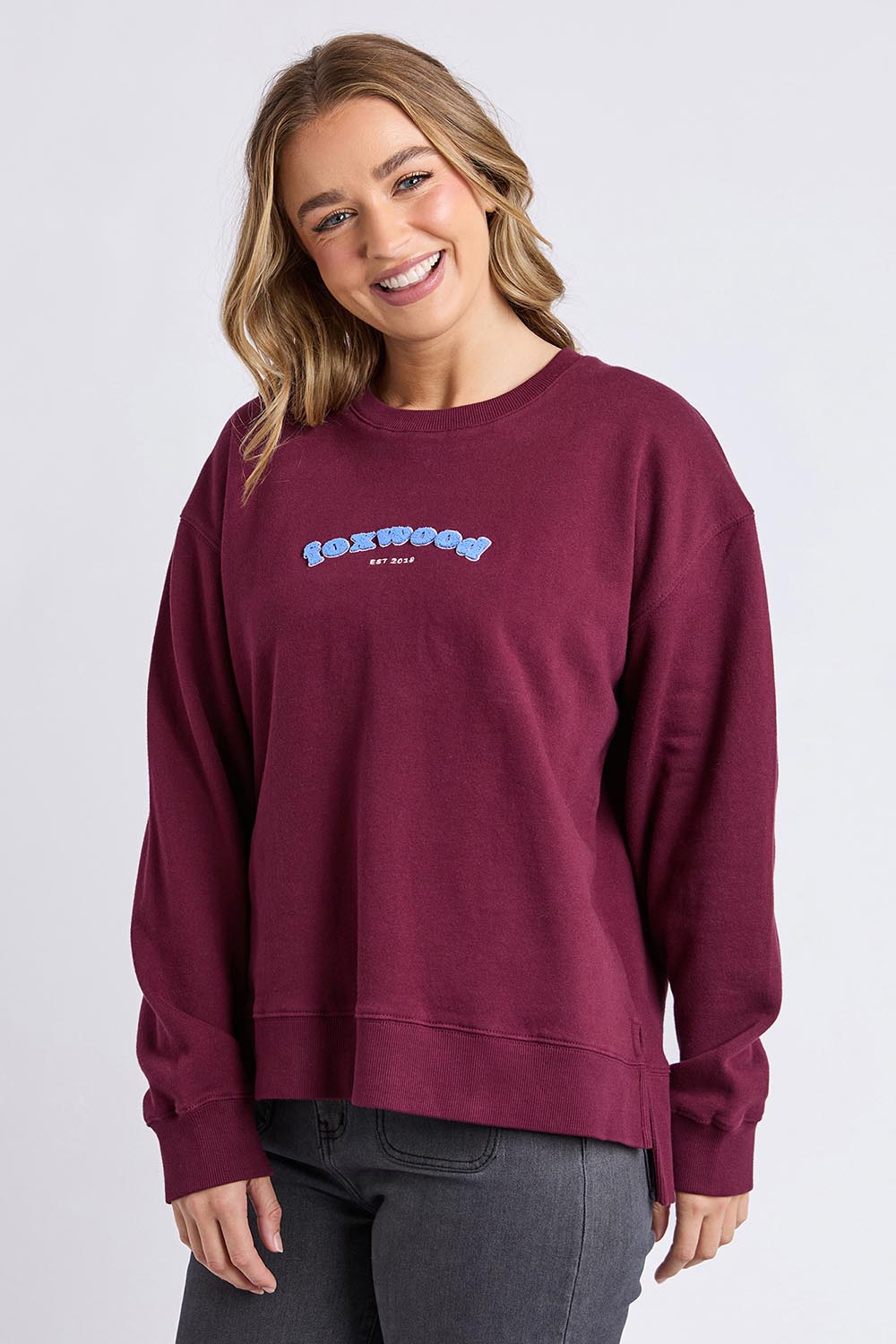 A model wearing the Solace Crew in colour Windwine (Red), from the front, cropped image