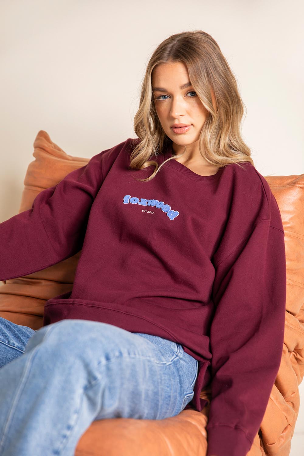 A model wearing the Solace Crew in colour Windwine (Red), from the front, showing the whole outfit