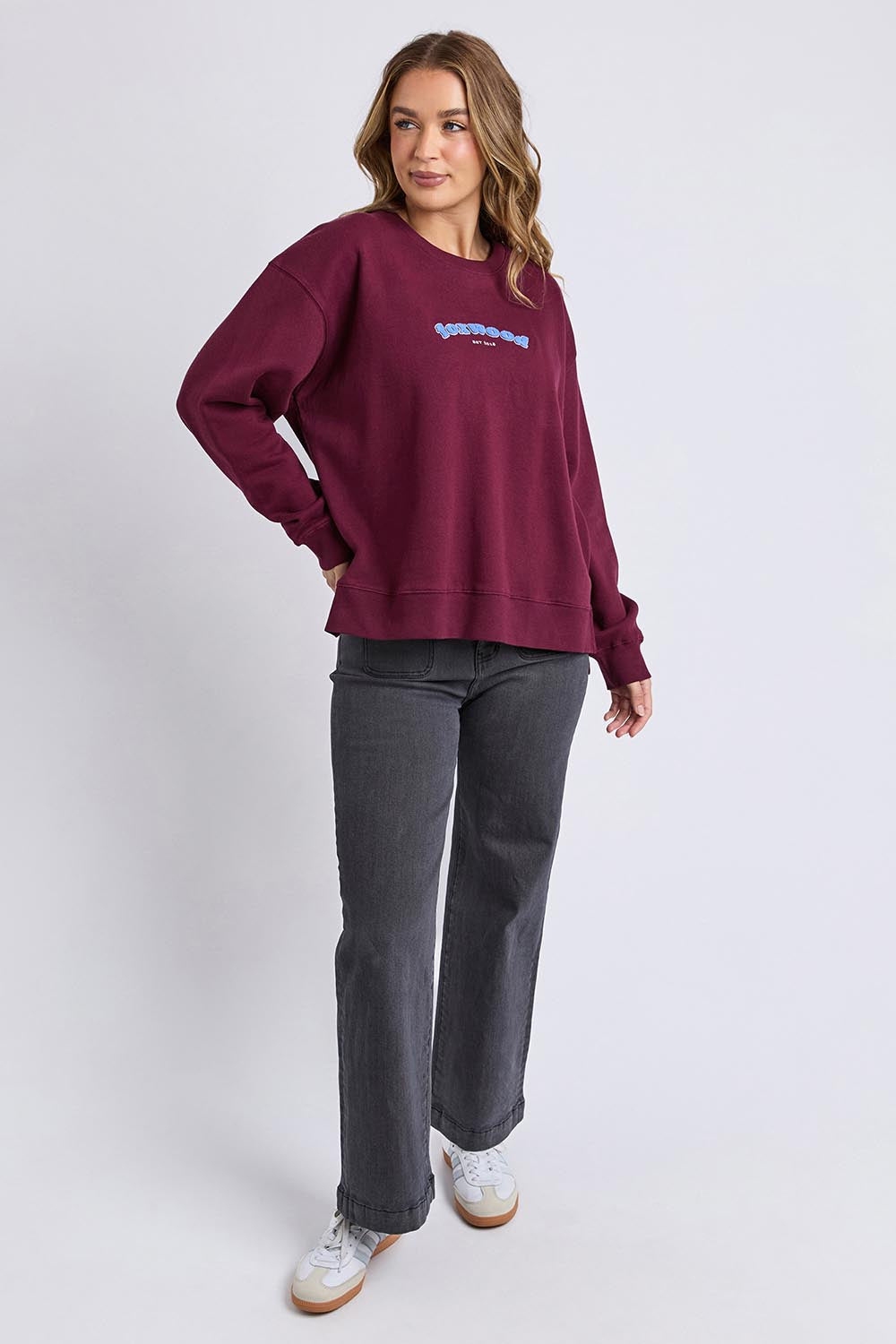 A model wearing the Solace Crew in colour Windwine (Red), from the front, showing the whole outfit