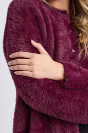A model wearing the Kenny Button Cardi in colour Windwine (Red), from the front, cropped image