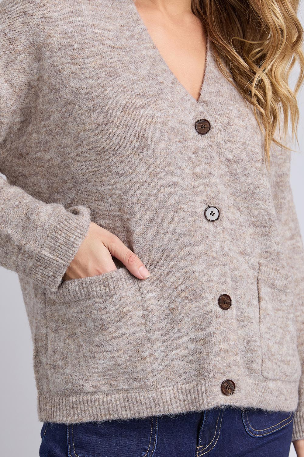 A model wearing the Emarie Cardi in colour Oatmeal, from the front, cropped image