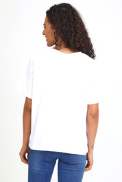 Model Pamelar wearing size 10 of the Studio Rose Tee – White in colour White, from an angle