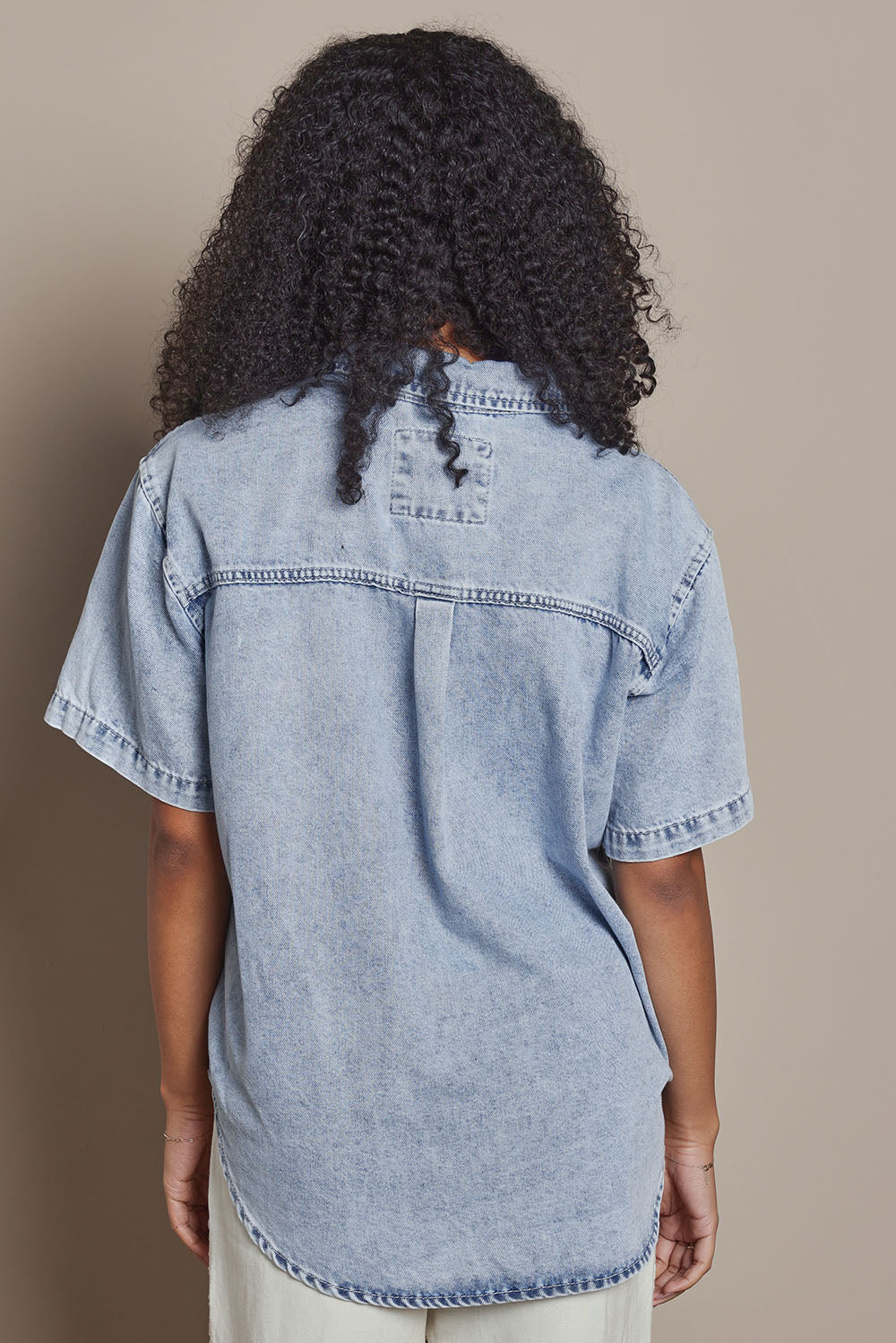 Model Ziara wearing size 10 of the Daisy Denim Ss Shirt in colour Lightblue (Blue), from the back