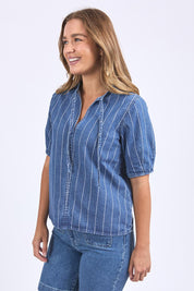 A model wearing the Tivoli Denim Top in colour Midblue (Blue), from the front, cropped image