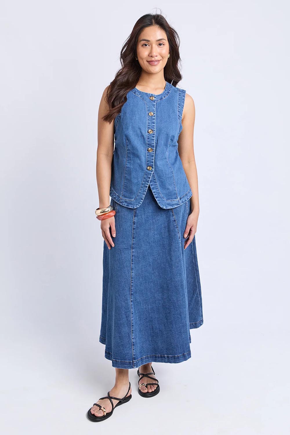 A model wearing the Abbott Denim Vest in colour Midblue (Blue), from the front, showing the whole outfit